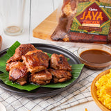 Cooked chicken thigh fillets on a banana leaf, served with peanut sauce and rice, with packaging in the background.