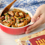 A bowl of pork salpicado served with rice, garnished with green onions, with a package of Clancy's Pork & Beans visible in the foreground.