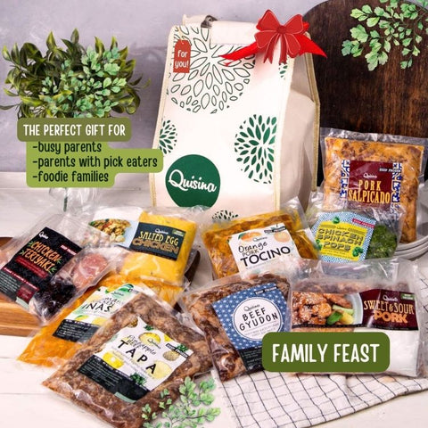 A gift set from Quisina titled 'Family Feast' featuring various packaged food items including teriyaki chicken, beef gyudon, pork salpicado, tocino, pineapple beef tapa, and salted egg chicken, presented in a thermal gift bag with a red ribbon on top.