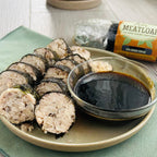 slices of nori-wrapped chicken meatloaf with teriyaki sauce on a plate
