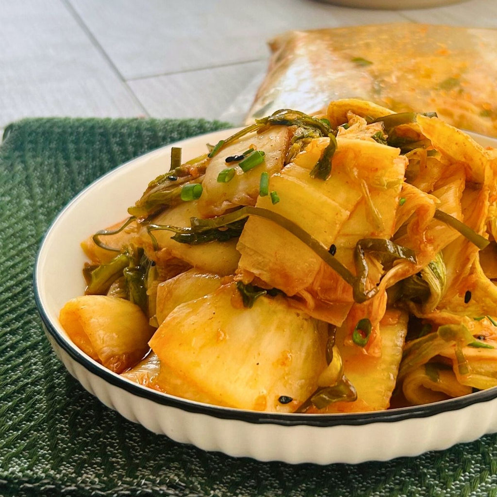 A bowl of Okinawa Kimchi, consisting of pickled vegetables, served on a white plate with a green mat underneath.